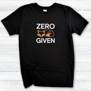 以下が含まれることがあります： 「ZERO GIVEN」の白文字とオレンジ色の寝ているキツネのグラフィックが特徴の黒いTシャツ。 デザインはTシャツの前面の中央に配置されています。 Tシャツは柔らかい素材で作られています。