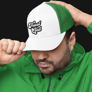 Puede incluir: Una gorra de camionero blanca y verde con un logotipo bordado en blanco y negro que dice "Trust in God".