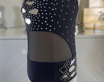 May include: A black dance leotard with a mesh panel and silver rhinestones. The leotard has a high neckline and a sleeveless design.