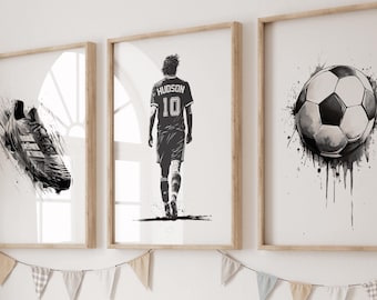 Puede incluir: Tres cuadros de pared con ilustraciones en blanco y negro de temática futbolística. El cuadro de la izquierda muestra una bota de fútbol, el central a un jugador con una camiseta con el nombre HUDSON y el número 10, y el de la derecha un balón de fútbol.