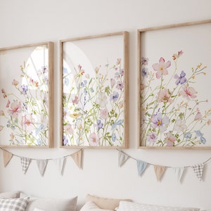 K&ouml;nnte beinhalten: Drei gerahmte Aquarelldrucke eines Blumenstrau&szlig;es mit rosa, lila und blauen Blumen auf wei&szlig;em Hintergrund. Die Rahmen sind aus hellem Holz und die Drucke sind in einer Reihe angeordnet.
