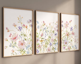 May include: A set of three framed watercolor prints featuring a delicate floral design with pink, blue, and yellow flowers on a white background.