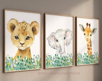 Puede incluir: Tres cuadros de pared con ilustraciones en acuarela de un cachorro de león, un elefante bebé y una jirafa, cada uno asomándose detrás de follaje verde. El texto AdorableNurseryNKids está impreso en la parte inferior central de la imagen.
