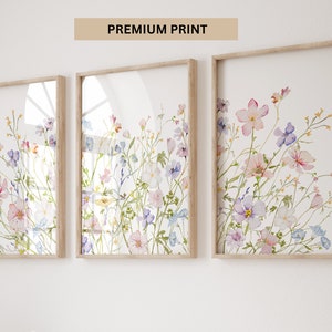 K&ouml;nnte beinhalten: Drei gerahmte Aquarelldrucke eines Blumenstrau&szlig;es mit rosa, lila und blauen Blumen auf wei&szlig;em Hintergrund. Die Rahmen sind aus hellem Holz.