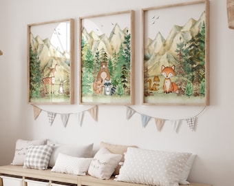 Op de afbeelding: Drie ingelijste aquarelprints met bosdieren in een bossetting. De prints tonen een hert, een beer met een wasbeer en een vos. De prints hangen aan een witte muur met een guirlande van vlaggen eronder.