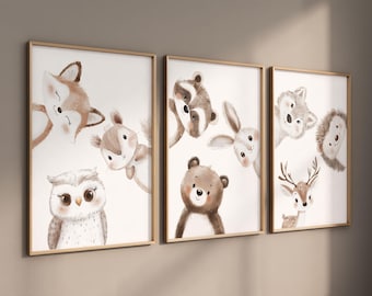 Op de afbeelding: Set van drie ingelijste prints met aquarel illustraties van bosdieren. De prints tonen een vos, een eekhoorn, een uil, een wasbeer, een konijn, een beer, een hert en een egel. De prints zijn in een lichtbruine lijst met een witte achtergrond.
