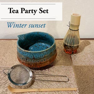 May include: A tea party set with a blue and brown ceramic bowl, a bamboo whisk, a metal strainer, and a bamboo scoop. The text "Tea Party Set" and "Winter sunset" are displayed in the image.