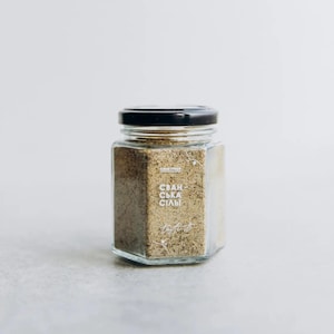 May include: A glass jar with a black lid filled with a brown spice blend. The label on the jar reads "Svan-ska Slalv" and "Taste It".