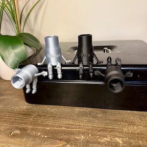 May include: Four socket wrenches with attached arms and legs are arranged on a black toolbox. Two are silver, one is black, and one is a darker gray. The silver wrenches are labeled "10mm" and the black wrench is labeled "0mm".