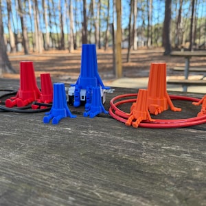 May include: Assortment of wire connectors in red, blue, and orange. The connectors have multiple prongs and are arranged on a wooden surface.