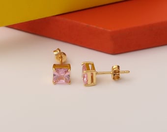 May include: A pair of gold stud earrings with pink square-shaped gemstones.