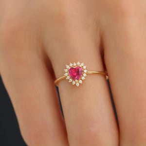 May include: A gold ring with a heart-shaped ruby surrounded by a halo of small diamonds.