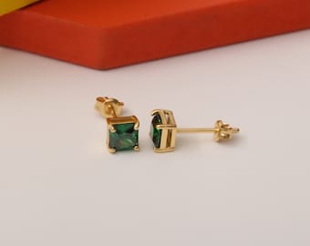 May include: A pair of gold earrings with square green gemstones.