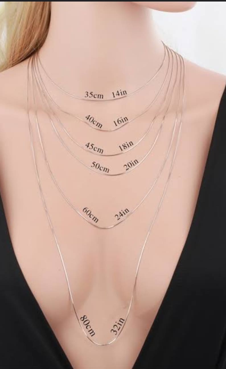Op de afbeelding: Een zilveren kettingketting in verschillende lengtes, vari&euml;rend van 14 inch tot 32 inch. De ketting wordt getoond op de nek van een model, met de lengtes aangegeven in zowel inch als centimeters.