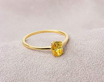May include: A gold ring with a yellow oval-shaped gemstone.