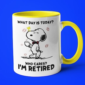 May include: White ceramic mug with a yellow handle and interior. The mug features a cartoon Snoopy character holding a coffee cup, with the text "WHAT DAY IS TODAY? WHO CARES? I'M RETIRED."