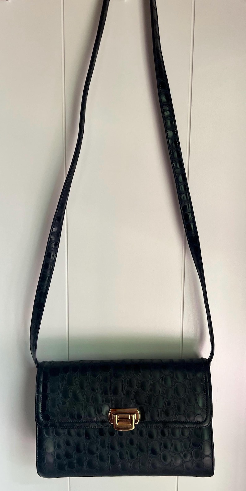 May include: A black crocodile-embossed leather shoulder bag with a gold clasp.