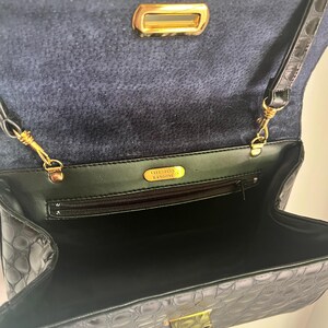 May include: Black crocodile embossed leather handbag with a gold clasp and a gold zipper. The bag has a black fabric lining and a gold label that reads "VALENTINO  B.ANGIONE".