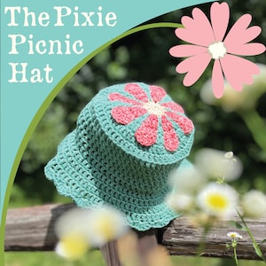 May include: A crocheted pixie picnic hat in a light teal color, featuring a pink and cream flower design on top. The hat has a scalloped brim and is displayed outdoors with the text "The Pixie Picnic Hat".