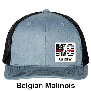 May include: A blue and black trucker hat with a graphic that says "K9 ARROW" with a silhouette of a person and dog, and the text "Belgian Malinois" below.