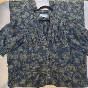 May include: A blue floral print dress with a V-neckline and button-down front. The dress features three-quarter sleeves with elastic cuffs and a fitted waist. The fabric has a pattern of green and blue floral designs.