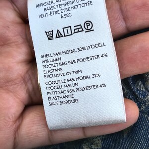 May include: A white clothing tag with black text detailing fabric composition and care instructions. The tag lists the shell as 54% modal, 32% lyocell, and 14% linen. It also includes washing symbols and the text "EXCLUSIVE OF TRIM."
