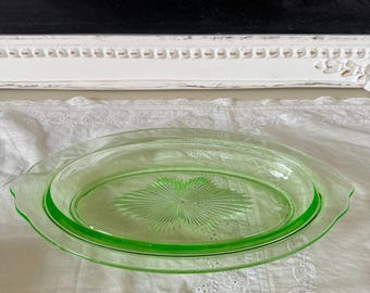 Op de afbeelding: Een vintage ovale serveerschaal van groen glas met een reliëfsterrenpatroon. De schaal heeft een deksel en is perfect om snacks of desserts te serveren.