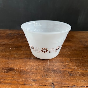 May include: White ceramic cup with a brown floral design around the rim.