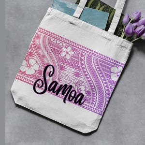 May include: A white tote bag with a pink and purple gradient design featuring floral and geometric patterns. The word "Samoa" is written in a cursive font. The bag contains books and purple tulips.