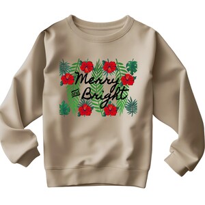 May include: A tan sweatshirt with a festive design. The graphic features the words "Merry and Bright" in black script, surrounded by red hibiscus flowers and green tropical leaves. The sweatshirt has long sleeves and a crew neck.