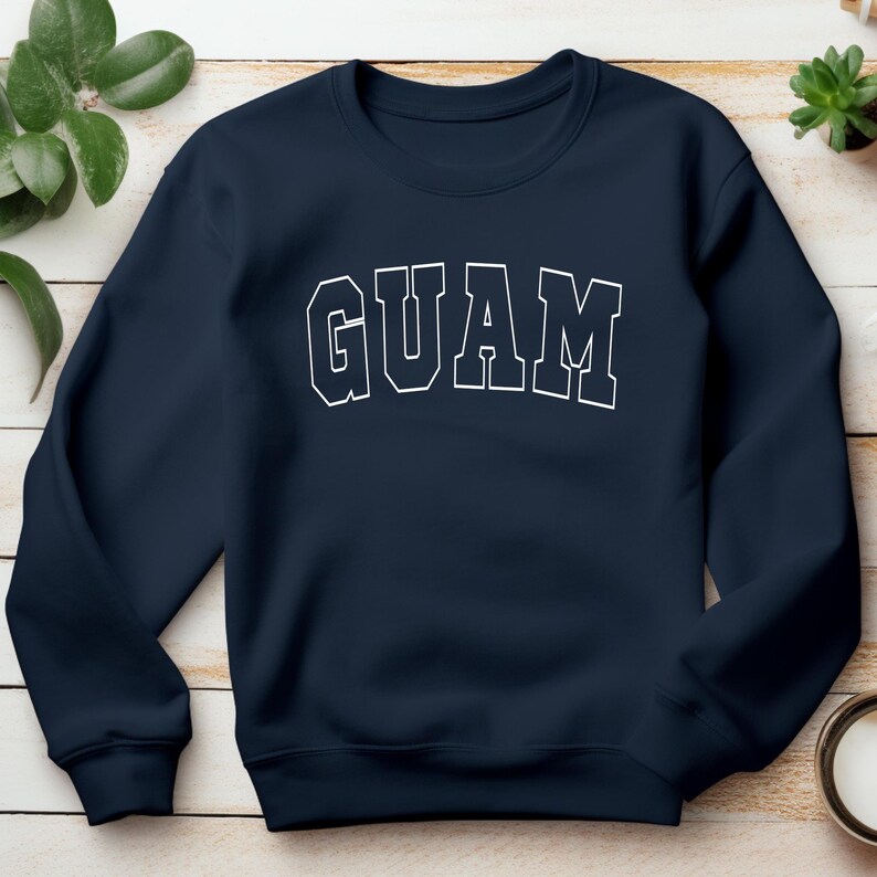 Op de afbeelding: Een donkerblauw sweatshirt met het woord "GUAM" in wit op de voorkant.