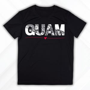 May include: Black t-shirt featuring the word "GUAM" in white, with each letter filled with detailed black and white designs. A small red heart sits below the word, with a red line beneath.