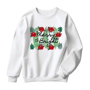 May include: White sweatshirt with a festive design. The design features red hibiscus flowers, green leaves, and the words "Merry and Bright" in black script. The sweatshirt is a crew neck style.