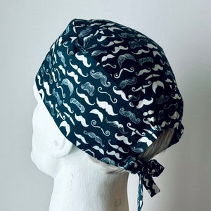 May include: A dark blue surgical scrub hat with a white mustache pattern. The hat has a tie at the back.