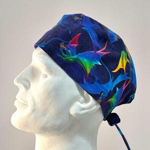 May include: A blue surgical scrub hat with a colorful dragon print. The hat has a tie at the back.