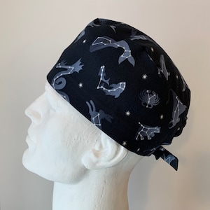 May include: Black scrub hat with a constellation pattern featuring various sea creatures, including a whale, seahorse, crab, and fish. The constellations are outlined in white with white stars on a black background.
