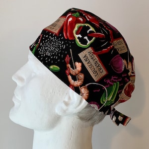 May include: Black scrub hat with a colorful print of various seafood and spices. The print includes shrimp, crawfish, peppers, onions, and garlic. The text "LOUISIANA" and "GUMBO" is visible on the hat.