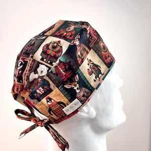 May include: A patterned scrub cap featuring a repeating design of various animals in winter attire. The cap is predominantly brown, green, and red, with a tie in the back. The design includes bears, deer, and penguins. The text "HEAD BOXER" is visible.