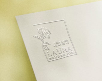 Può includere: Etichetta bianca in rilievo con un motivo floreale e il testo "Questo libro appartiene a Laura Henderson".