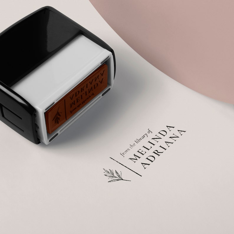 May include: A black and white self-inking stamp with a brown ink pad. The stamp reads "from the library of MELINDA ADRIANA".