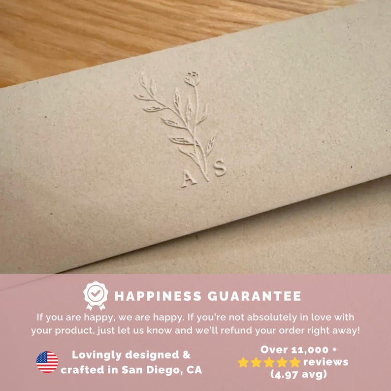 May include: A light beige paper envelope featuring a debossed botanical illustration of a leafy stem with the letters A and S positioned below. The lower section includes text stating Happiness Guarantee, refund policy, and design location details.