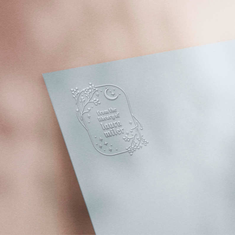 May include: White embossed stamp featuring a crescent moon and stars, encircled by a floral design. The text reads "From the library of Laura Miller."