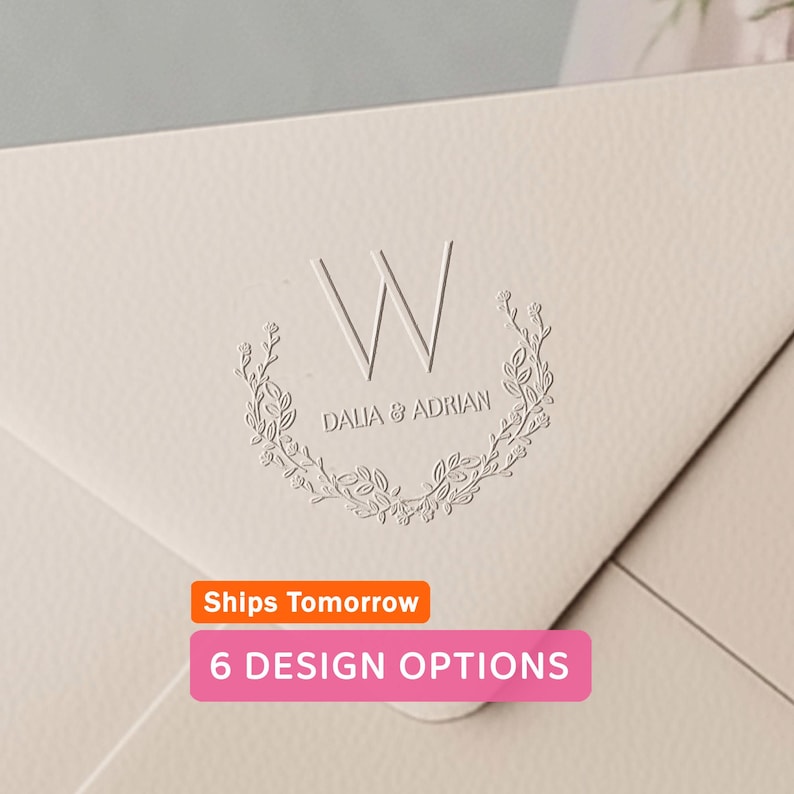 May include: Close-up of a cream-colored envelope with a debossed design. The design includes a large letter "W" above the names "DALIA & ADRIAN" within a floral wreath. The image also shows text that says "6 DESIGN OPTIONS".