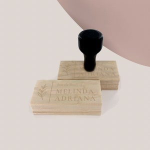 May include: Two wooden stamps with a leafy design and the text "from the library of Melinda Adriana". The top stamp has the text "from the library of Melinda Adriana".