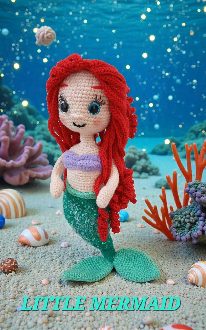 May include: A crocheted Little Mermaid doll with red hair, a purple top, and a green tail. The doll is set against a backdrop of an underwater scene with coral and seashells. The text "LITTLE MERMAID" is at the bottom.