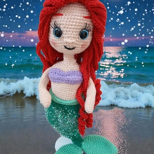May include: A handmade crochet mermaid doll with red hair, a purple top, and a green sequined tail. The doll is posed on a beach with a starry sky and a full moon in the background.
