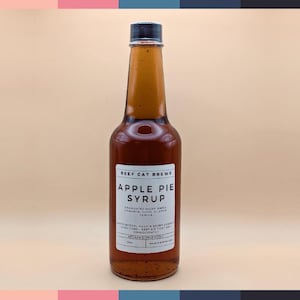 May include: A glass bottle of brown apple pie syrup with a white label that reads "Beef Cat Brews Apple Pie Syrup". The label lists the ingredients as "Granulated Sugar, Maple, Cinnamon, Clove, Allspice, Vanilla".