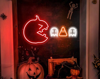 May include: A neon sign depicting a pumpkin-shaped Pac-Man character eating three ghost characters. The sign is lit in red and orange and is displayed against a dark background with Halloween decorations.