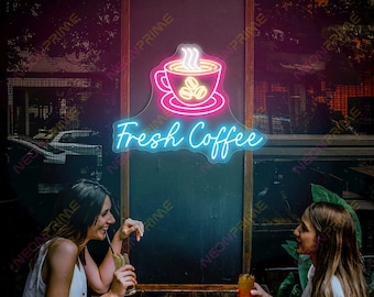 Może przedstawiać: Neonowy szyld z motywem filiżanki kawy i napisem "Fresh Coffee" w kolorze niebieskim. Znak jest zamontowany na ciemnym tle. Dwie osoby siedzą przy drewnianym stole, popijając napoje. Scena rozgrywa się na zewnątrz, z rozmytym tłem.
