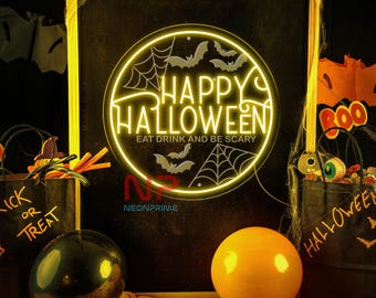 Op de afbeelding: Een neonbord met de tekst "Happy Halloween" in een cirkelvormig ontwerp, met vleermuizen en spinnenwebben. Het bord bevat ook de zin "Eat Drink and Be Scary". Zwarte traktatiezakken en ballonnen staan op de voorgrond.